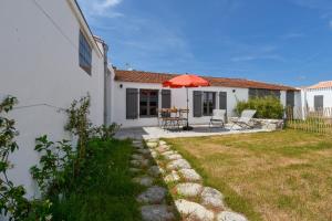 a patio with a table and an umbrella in a yard at Detente dans une jolie maison a Noimoutier in Noirmoutier-en-l'lle