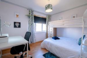 1 dormitorio con cama, escritorio y litera en Seaside Home with Sea Views, en Balmedie
