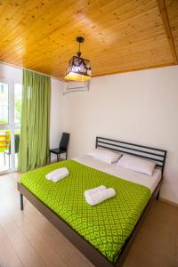 a bedroom with a large bed with a green blanket at Kaprovani Sand in Ureki