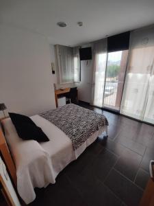 a bedroom with a bed in a room with windows at Hostal Manel in Pineda de Mar