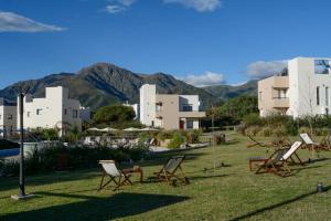 a group of chairs sitting on the grass in front of buildings at Apart Hotel Los alazanes in Capilla del Monte