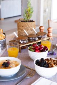 einen Frühstückstisch mit Schalen mit Obst und Orangensaft in der Unterkunft ERIKOUSA Palace by Corfuescapes in Ereikoússa