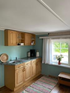 a kitchen with wooden cabinets and a sink and a window at Aaviku Holiday Houses in Vanamõisa +16 photos