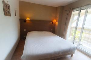 a bedroom with a white bed and a window at Hotel Alicia Auray Le Bono in Le Bono