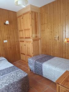 2 camas en una habitación con paredes de madera en APARTAMENTOS Y HABITACIONES RURALES "El Corral", en Cañizares