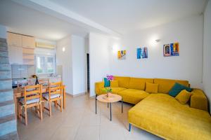 a living room with a yellow couch and a table at Apartments Novo Mulo in Tivat +29 photos