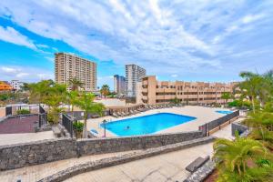 an outdoor swimming pool with palm trees and buildings at Gina s Sun Terrace in Playa Paraiso