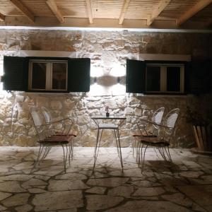 Paxos Dream House في Vlachopoulátika: غرفة بها كراسي وطاولة أمام جدار حجري