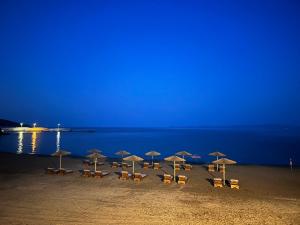 a group of chairs and umbrellas on a beach at night at Pension Karvounoskala in Stratoni
