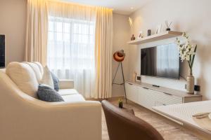 a living room with a white couch and a television at Luxe Studio and 1 bedroom Apartment in Naivasha