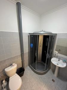 y baño con ducha, aseo y lavamanos. en Hotel Bereke, en Atyraū