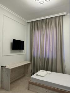 a bedroom with a bed and a television on the wall at Hotel Bereke in Atyrau