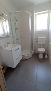 La salle de bains est pourvue d'une douche, de toilettes et d'un lavabo. dans l'établissement Apartmani URANIJA, à Sveti Filip i Jakov