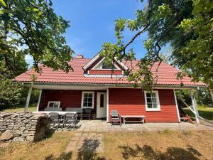 Aaviku Holiday Houses في Vanamõisa: بيت احمر امامه طاوله وكراسي