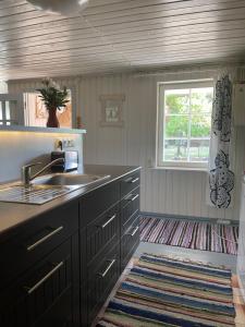 a kitchen with black cabinets and a sink and a window at Aaviku Holiday Houses in Vanamõisa