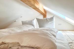 - un lit mansardé avec des draps et des oreillers blancs dans l'établissement Alpen Lodge in Osterhofen - Berge, Ruhe & Natur, à Bayrischzell