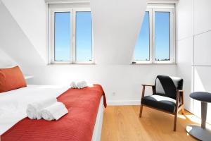 um quarto com uma cama, uma cadeira e janelas em Brand New River View Apartment Belém - 1 bedroom, A/C em Lisboa