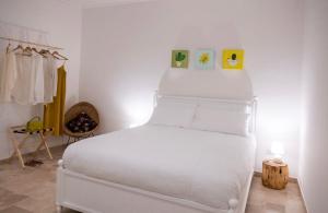 ein weißes Bett in einem weißen Zimmer mit Bettblende in der Unterkunft Masseria Spiga in Gravina in Puglia
