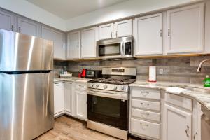a kitchen with white cabinets and a stainless steel refrigerator at Modern Newark Vacation Rental Near Downtown! in Newark