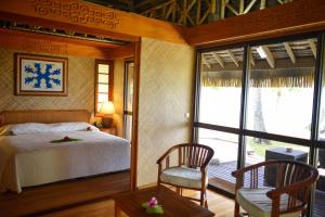 1 dormitorio con 1 cama, 2 sillas y ventana en Hotel Kia Ora Resort & Spa en Avatoru