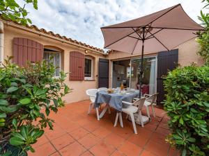 a table and chairs with an umbrella on a patio at Holiday Home Le Hameau des Capellans by Interhome in Saint-Cyprien-Plage