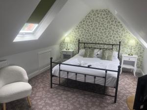 a bedroom with a bed and two tables and a chair at Penny Farthing Hotel & Cottages in Lyndhurst