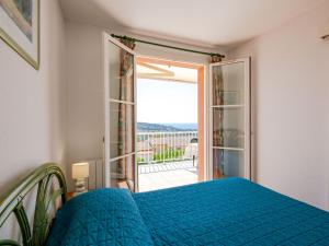 a bedroom with a blue bed and a sliding glass door at Apartment Le Petit Village-2 by Interhome in La Garonnette-Plage