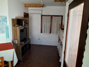 um pequeno quarto com uma televisão e um quarto com uma janela em I Casa de invitados cerquita de la playa buenas olas em La Aguada