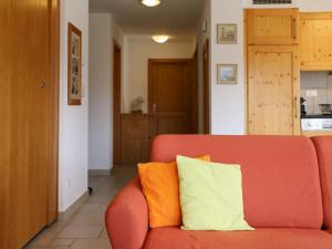 a red couch with an orange and white pillow on it at Apartment Domaine des Reines D1A by Interhome in Nendaz