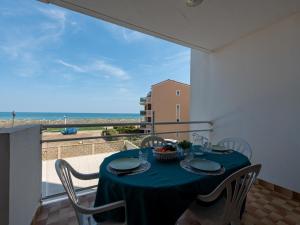 a table with a blue table cloth on a balcony with the ocean at Apartment Amphitrite by Interhome in Le Barcarès