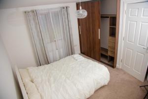 a bedroom with a white bed and a closet at Beautiful 5 Bedroom House in Glasgow in Cambuslang