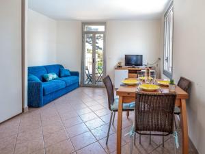 a living room with a table and a blue couch at Apartment La Bouée by Interhome in Antibes