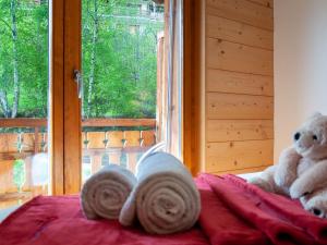 a teddy bear sitting on a bed next to a window at Apartment Les Cimes Blanches B 401 by Interhome in Nendaz