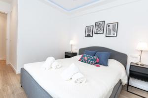 Schlafzimmer mit einem Bett mit weißer Bettwäsche und blauen Kissen in der Unterkunft Acogedor apartamento en Estepona centro by Rent Me in Estepona