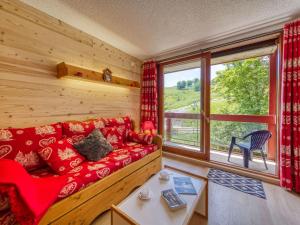 a living room with a red couch and a large window at Apartment Lunik Orion-38 by Interhome in Le Corbier