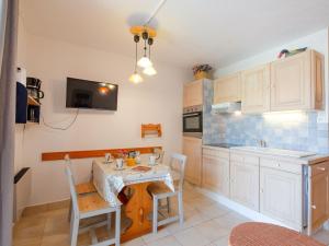 a kitchen with a table and chairs and a kitchen with white cabinets at Apartment Les Hauts des Issambres-11 by Interhome in Les Issambres