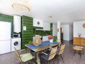 una cucina con tavolo, sedie e piastrelle verdi di Apartment La Carbonera by Interhome a Port de la Selva