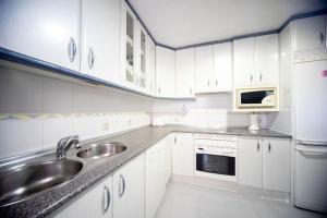 a white kitchen with a sink and a microwave at Las Retamas, Alcorcón in Alcorcón