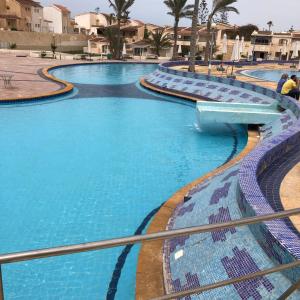 uma grande piscina com água azul num resort em فندق جراند كليوباترا الساحل الشمالى المنتزه ك80 em El Alamein