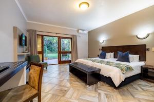 um quarto de hotel com uma cama e uma secretária em Hotel Numbi & Garden Suites em Hazyview