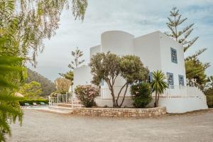 ein weißes Haus mit Bäumen davor in der Unterkunft Villa Sa Bassa, Amazing seaviews and great Pool in Portinatx