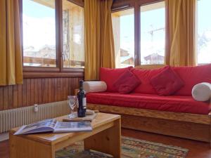 a red couch in a living room with a table at Apartment Les Grandes Balmes I et II - Le Lac-9 by Interhome in Tignes