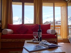 un soggiorno con divano rosso e tavolo con bicchieri da vino di Apartment Les Grandes Balmes I et II - Le Lac-9 by Interhome a Tignes
