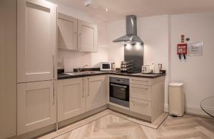 a kitchen with white cabinets and a sink at The Castle Collection - 5 Union Court in Liverpool