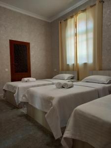 ein Zimmer mit 3 Betten und Handtüchern darauf in der Unterkunft Guest house Zebiniso in Samarkand