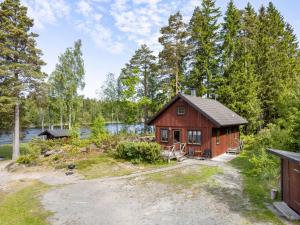 uma cabana vermelha na floresta ao lado de um lago em Chalet Kasen Sjökanten by Interhome em Färgelanda