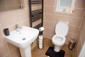 a bathroom with a white toilet and a sink at Beautiful 5 Bedroom House in Glasgow in Cambuslang