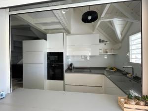 a kitchen with white cabinets and a black refrigerator at Pitaya - T3 cosy en duplex avec cuve in Saint-François