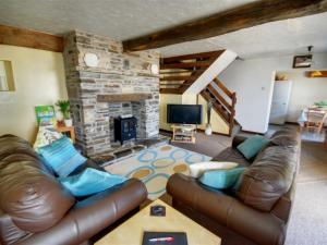 a living room with a leather couch and a fireplace at Holiday Home Mill Court by Interhome in Swimbridge