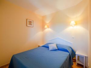 a small bedroom with a blue bed and two lights at Apartment Le Hameau des Issambres-5 by Interhome in Les Issambres